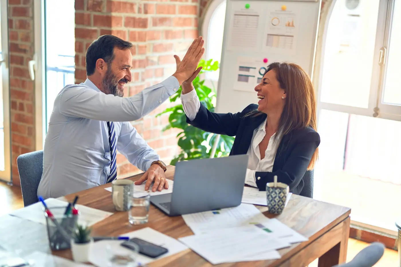Two colleagues high-fiving after a successful project