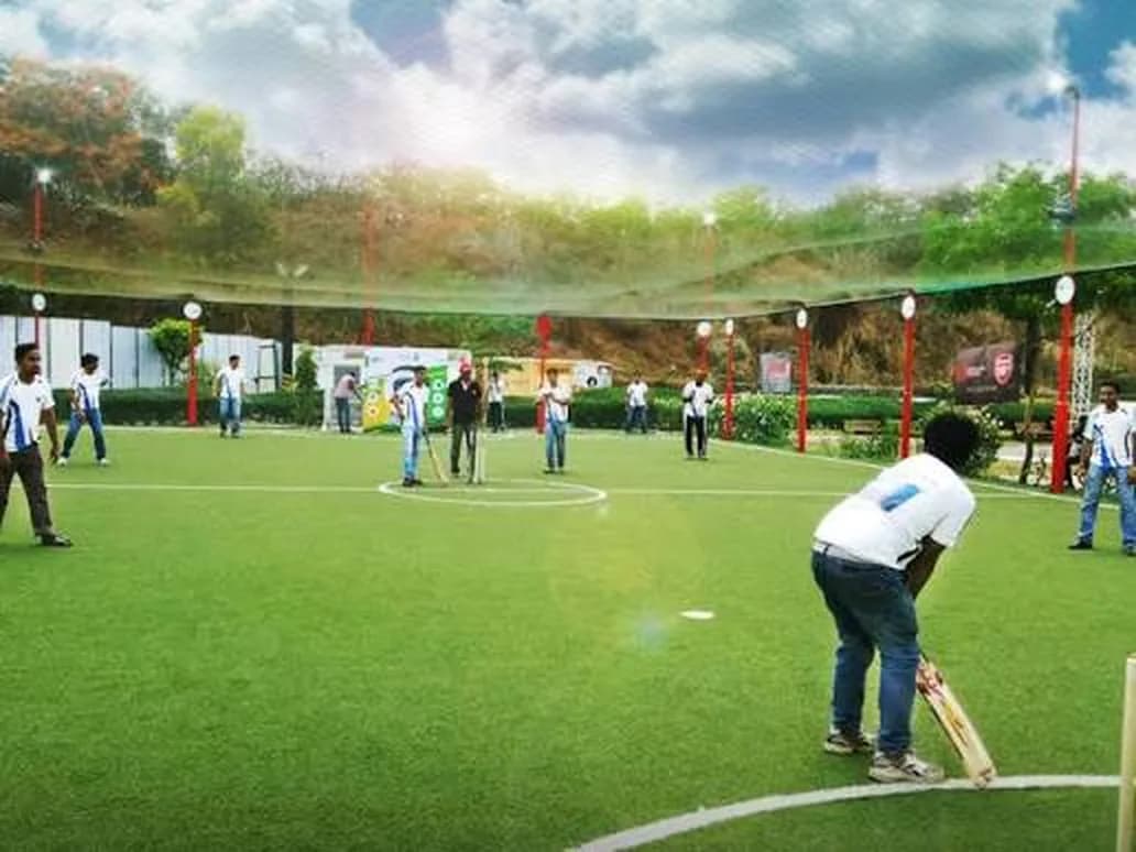 Colleagues playing cricket together on a turf ground